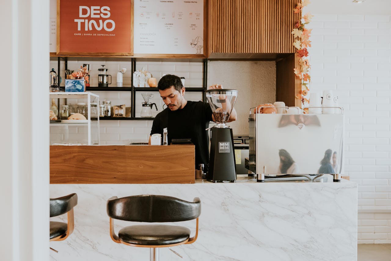 services-02 A barista in a contemporary café makes coffee behind a marble counter.